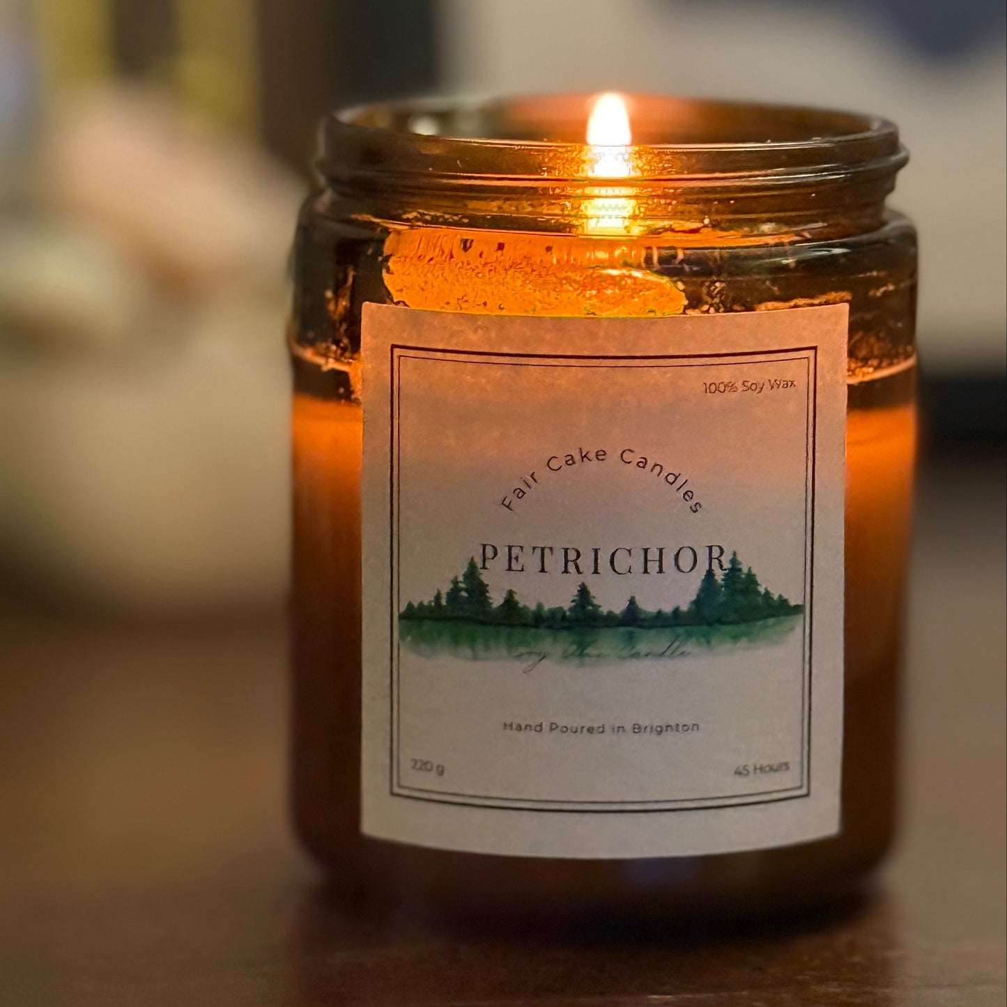 Petrichor candle lit on a wooden surface. Hand poured candles by Fair Cake Candles.