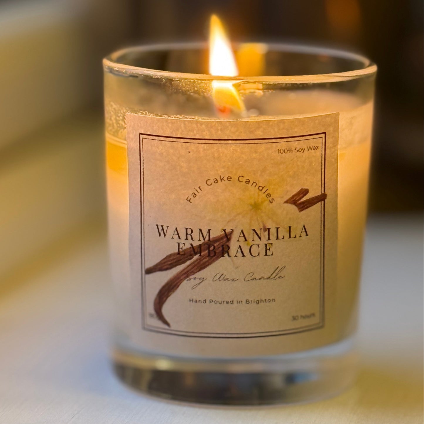 A lit Warm Vanilla Embrace candle by Fair Cake Candles. Hand poured candles in Brighton.
