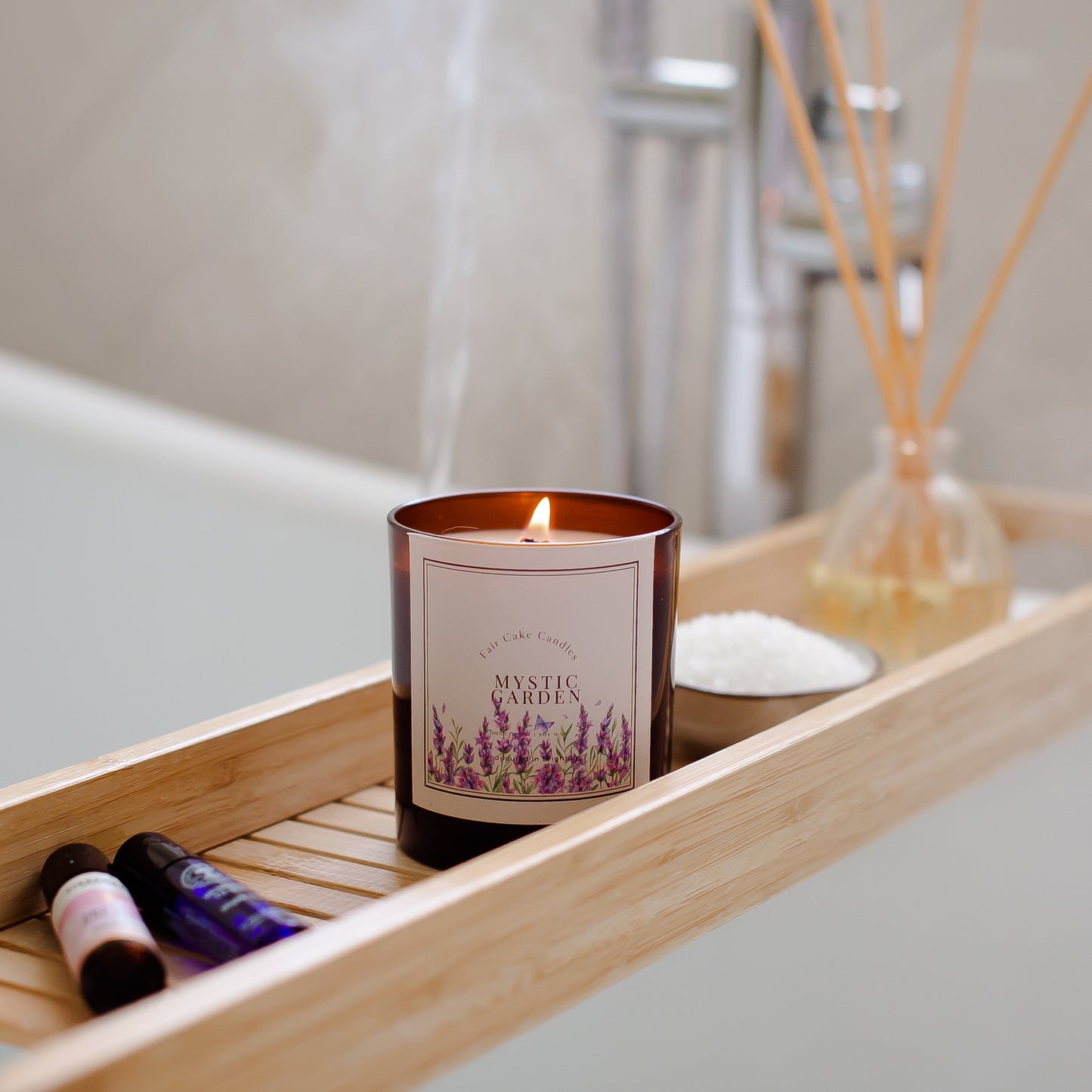 Candle labeled 'Mystic Garden' on a wooden tray with bath salts and oils in a bathroom setting.